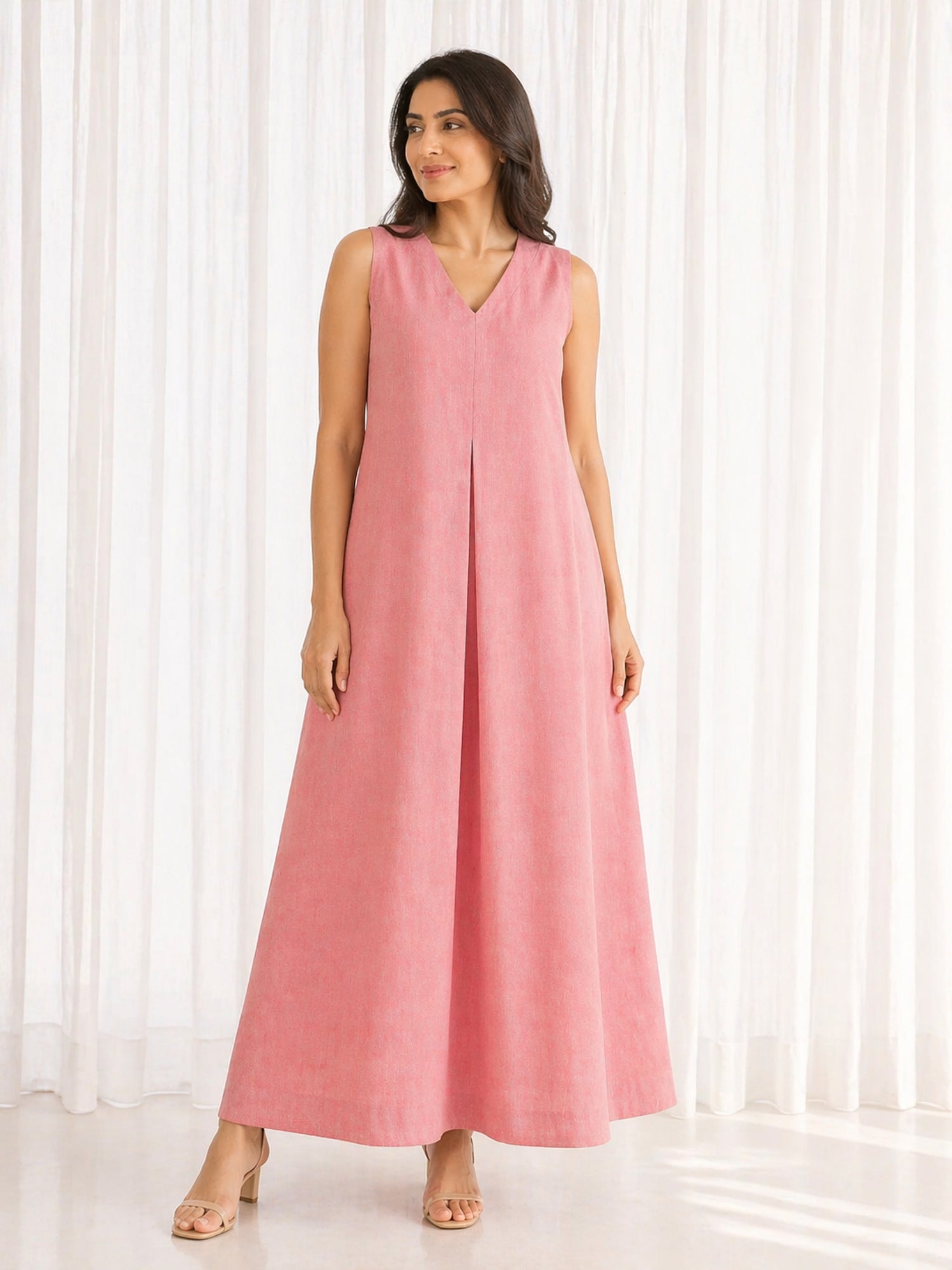 Full length front shot of peach sleeveless handloom ikat maxi dress styled on model in outdoor setting.