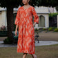 Front view of an orange ikkat cotton dress captured in natural light, with the model posing playfully outdoors.