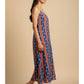 Model walking in handmade ikat cotton noodle strap dress with blue and red stripes, showcasing fluid movement and relaxed summer styling.